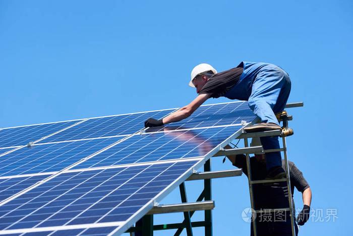 专业工人团队使用不同的设备在绿色金属结构上安装太阳能电池板创新的